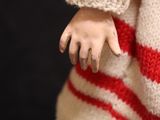 a close up of a doll wearing a red and white sweater