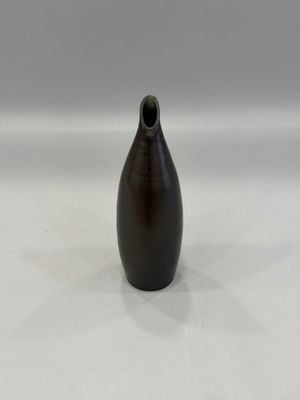 un vase noir posé sur une surface blanche