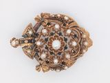 une broche en or ornée de perles, posée sur un fond blanc