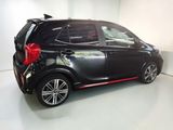 the back end of a small black car parked in a white room