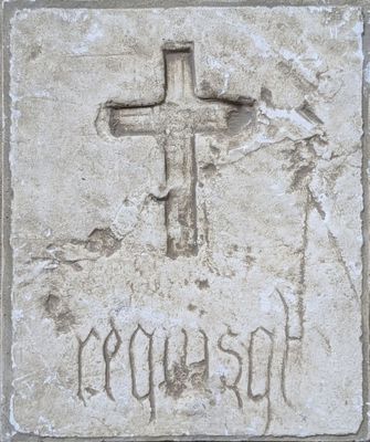 a stone plaque with a cross on it with the word jesus carved into it
