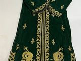 a green and gold embroidered robe with peacocks on it
