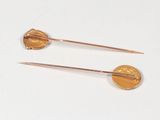 pair of gold colored pins with a coin in the middle of them