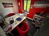a red chair in the corner of a room with a white desk