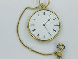 une petite montre de poche en or, attachée à une chaîne