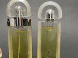 two bottles of perfume sitting next to each other on a table