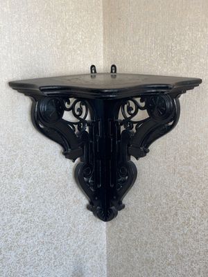 une étagère noire fixée au mur, dans un coin de la pièce