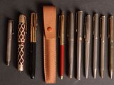 Plusieurs stylos et un stylo sont alignés sur une table