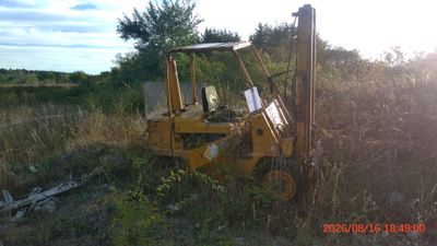 a tractor that is sitting in the grass by a pole