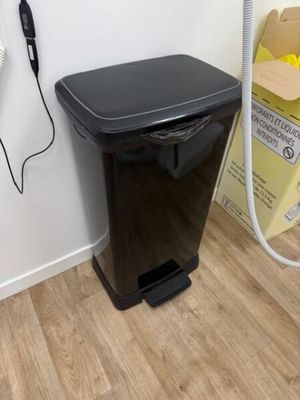 une poubelle noire posée par terre à côté d'un téléphone