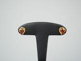 une paire de boucles d'oreilles en forme de cœur, dorées et rouges, posées sur un support noir