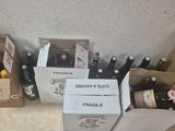 Des bouteilles de vin sont alignées par terre, à côté de cartons.