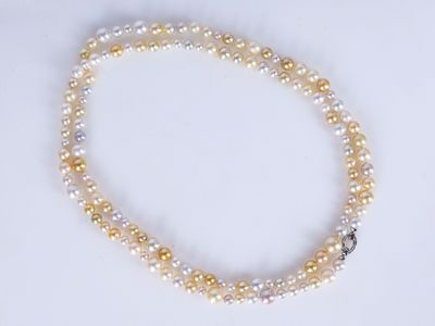 un gros plan d'un collier de perles blanches et jaunes posé sur une surface blanche