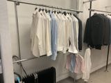 a lot of shirts hanging on a rack in a room