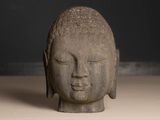 statue of a buddha head on a table with a black background