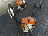 two chainsaws sitting on the ground next to a wall
