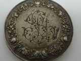 a silver coin with a monogram on it