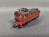 un petit train rouge sur les rails, sur un fond gris