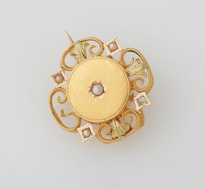an image of a gold broochle with a pearl in the center
