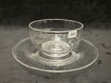 une tasse en verre et sa soucoupe posées sur une soucoupe
