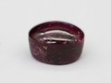 a close up of a red stone on a white surface