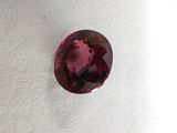 a close up of a red garnet stone on a white surface
