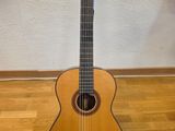 une guitare acoustique posée sur un parquet, près d'un mur
