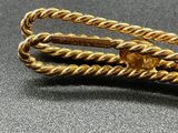 gold plated tie bar with twisted rope on a black surface