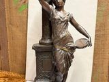 bronze statue of a woman holding a pot and a bird on top of a pedestal