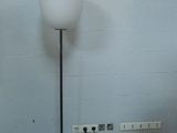 a lamp that is sitting on the floor next to a wall