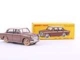 une petite voiture devant une boîte de jouets posée sur une surface blanche