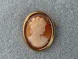 Une broche en or représente le profil d'une femme.