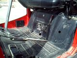the interior of a red vehicle with the door open and a steering wheel in the back