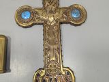 a gold cross with blue stones on it next to a lighter