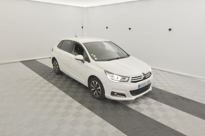 La voiture blanche est garée dans le garage de la maison.