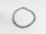 un gros plan d'un bracelet de perles posé sur une surface blanche