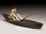 sculpture of a man in a canoe with a dog in it