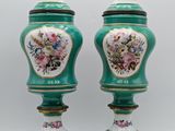 pair of green vases with floral designs on them sitting on a table