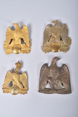 quatre broches en forme d'aigle en or et une clochette dorée sur un fond blanc