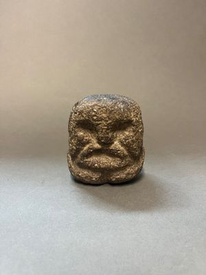 une photo d'une petite statuette représentant un visage, posée sur une table