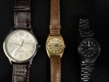three different watches are lined up on a black surface