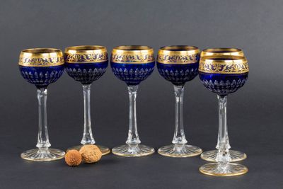 quatre verres à vin aux bords dorés, avec un bouchon posé devant chacun d'eux