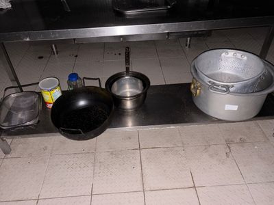 des casseroles et des poêles sont posées sur une étagère métallique dans une cuisine