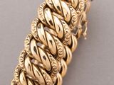 a close up of a gold bracelet on a gray surface