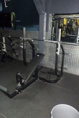une salle de sport équipée d'un banc, d'haltères et d'une poubelle