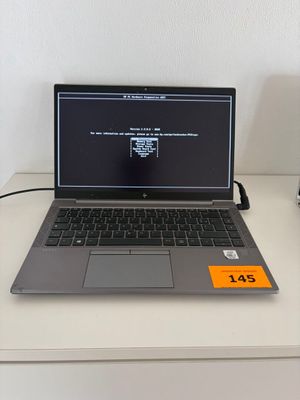 un ordinateur portable posé sur un bureau, à côté d'une lampe