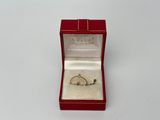 une petite bague dans une boîte rouge posée sur une surface blanche