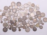 a pile of old silver coins on a white surface