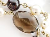 a close up of a necklace with pearls and beads