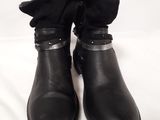 black leather boots with bows on the side of them on a white surface